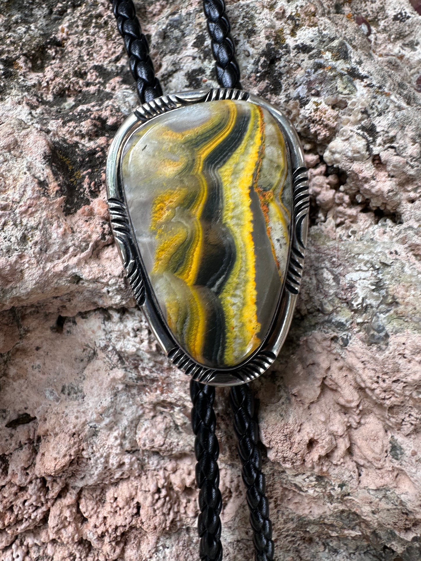 Bolo tie with a stone and metal design on a textured surface